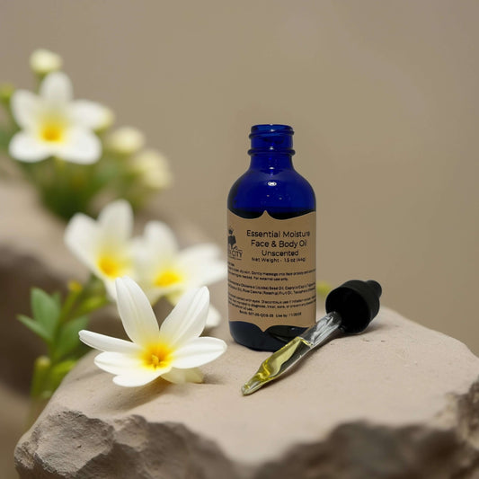 POS Small-Batch Hydration Unscented Face and Body Oil in blue glass bottle with dropper, surrounded by white flowers.