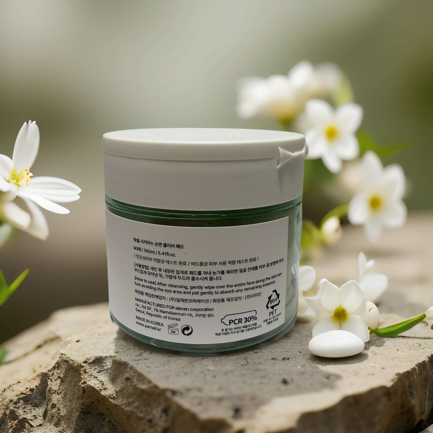 Cicamanu Cotton Clear Pad by Parnell on stone with flowers, showcasing packaging details in a natural setting.