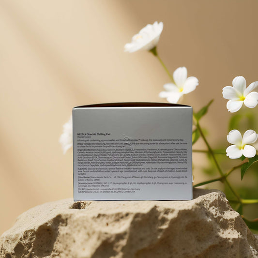 Soothing and Cooling Toner Pads by NEEDLY, with ingredient details on the packaging in a serene botanical setting.