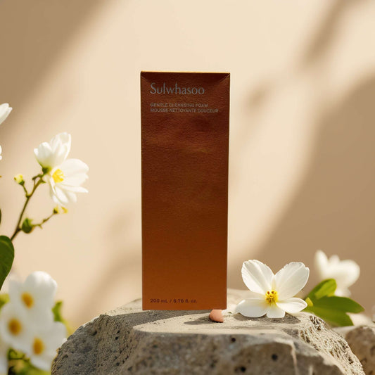 Sulwhasoo Gentle Cleansing Foam packaging on a stone surface with floral accents, 6.8 fl oz.