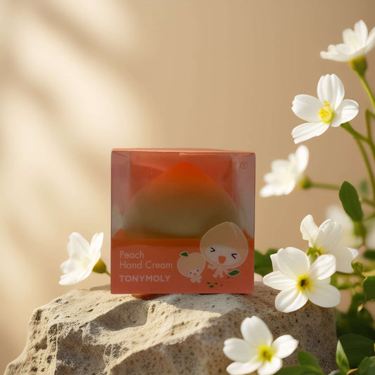 TONYMOLY Peach Hand Cream in peach-shaped container, hydrating formula surrounded by white flowers.