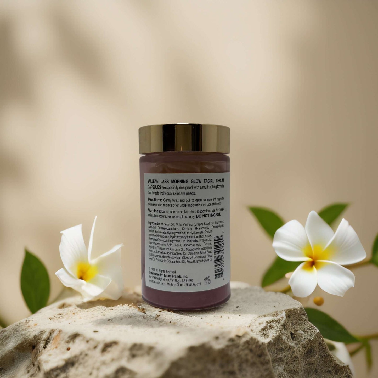 Valjean Labs Morning Glow Face Serum Pods bottle with floral accents on stone background.