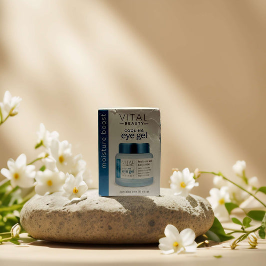 Vital Beauty Cooling Eye Gel on a stone, surrounded by white flowers, for de-puffing and hydrating tired eyes.