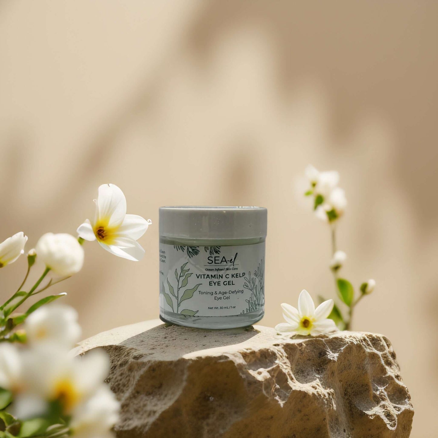 Vitamin C Kelp Eye Gel by SEA-el on a stone, surrounded by flowers, promoting brightening and puffiness control.