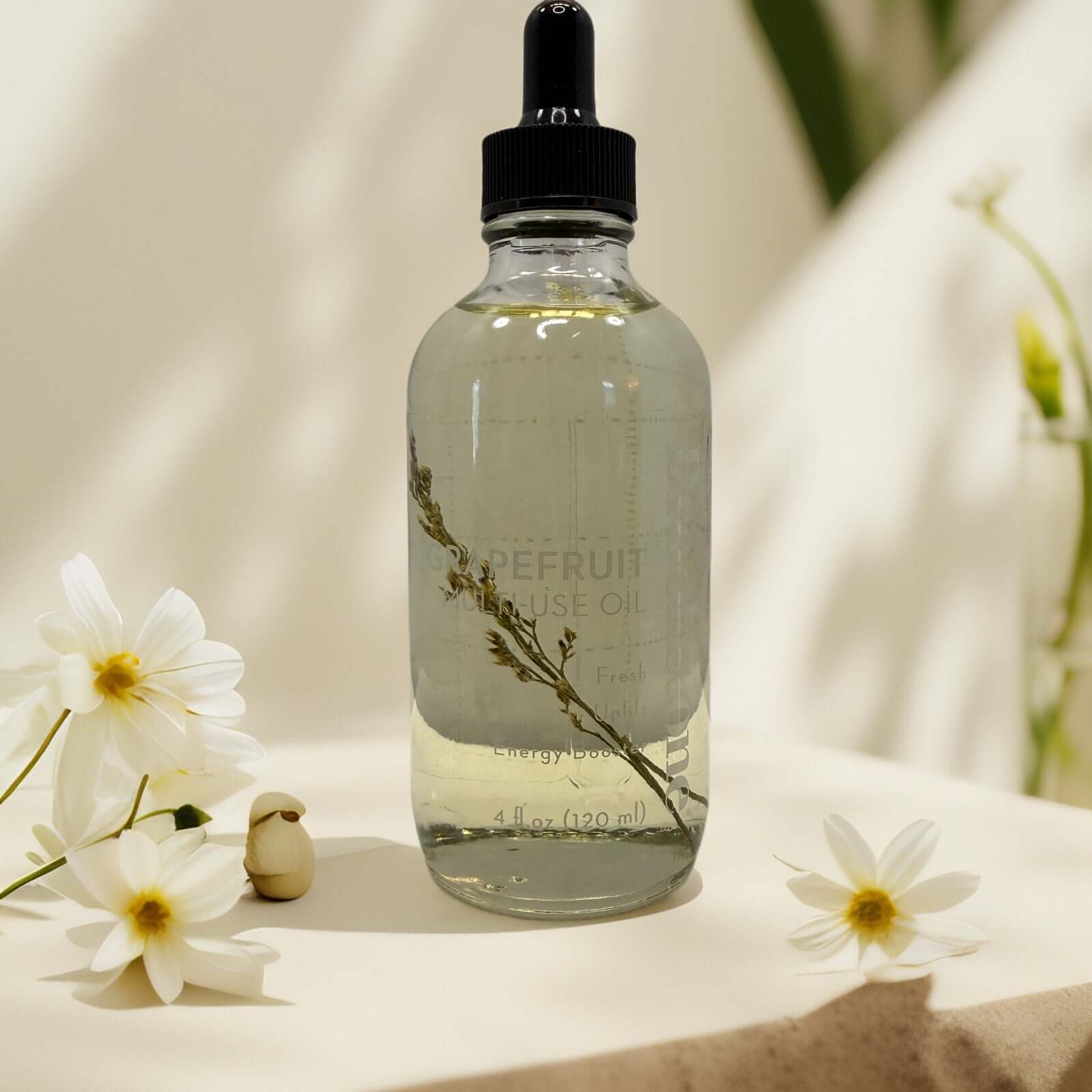 Grapefruit multi-use oil bottle with white flowers and dropper.