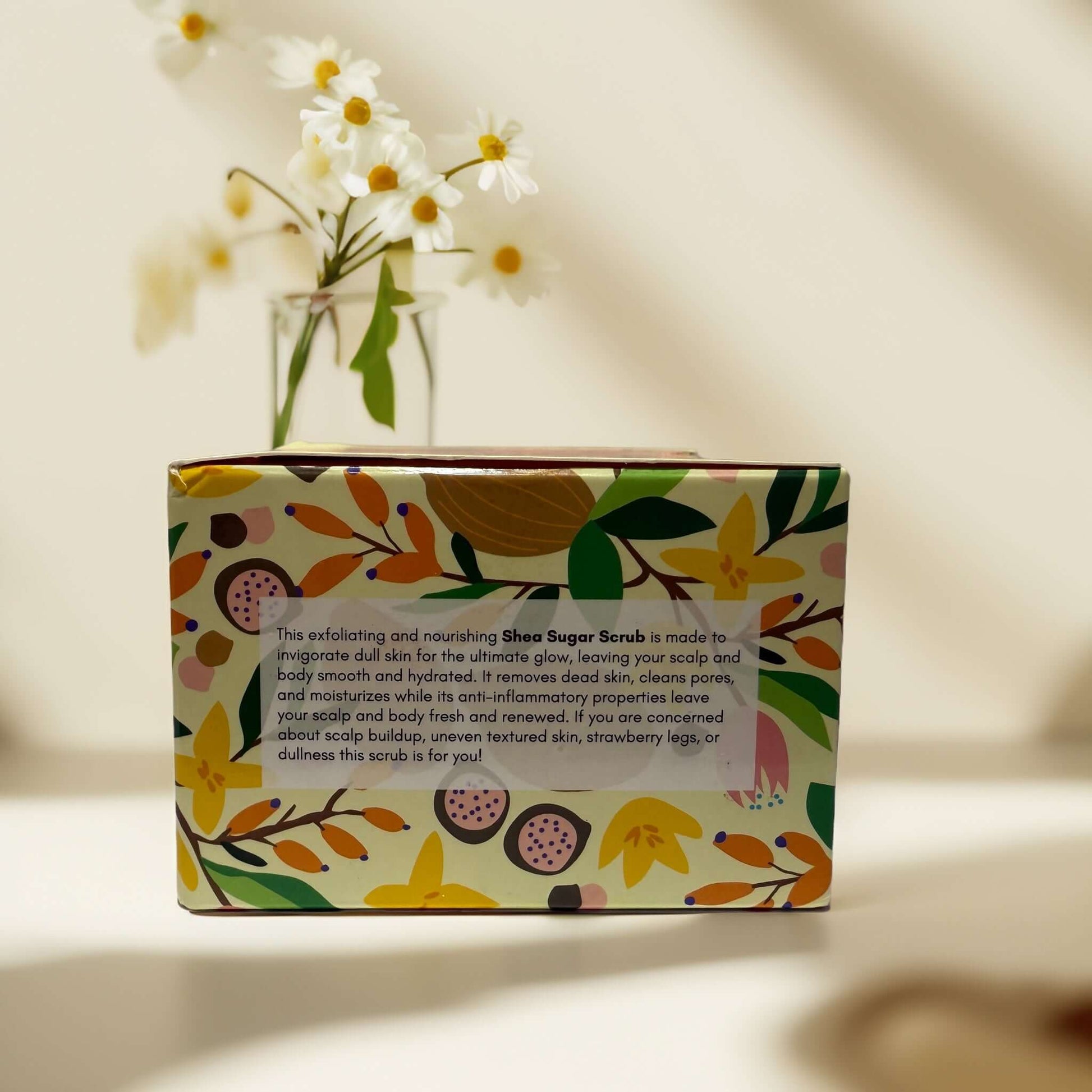 Flora & Noor Shea Sugar Scrub packaging on a table.