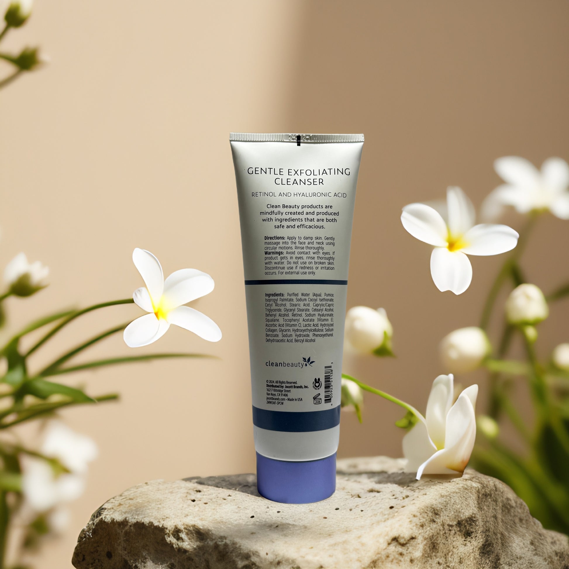 Gentle Exfoliating Cleanser by Clean Beauty with retinol and hyaluronic acid on a stone surface with flowers.