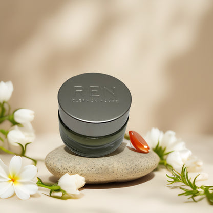 REN Clean Skincare Evercalm Rescue Mask on stone with flowers, hydrating cream for sensitive skin.