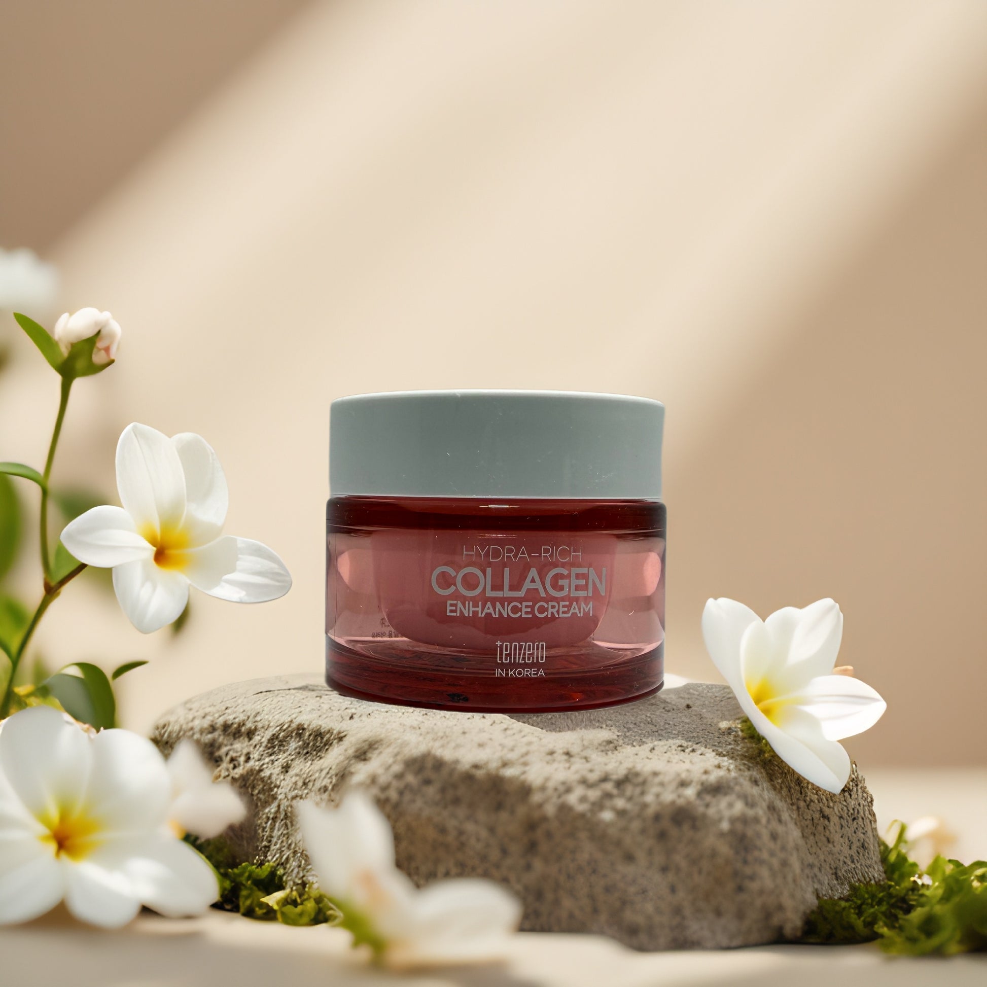 Tenzero Firm & Smooth Collagen Enhance Cream jar surrounded by flowers on a stone surface.