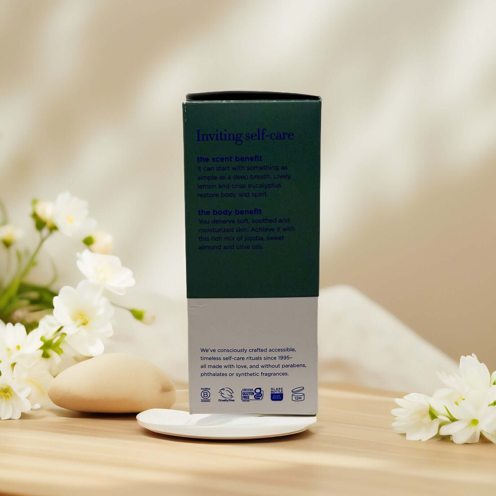 Body Boost Bath Oil packaging display with flowers.