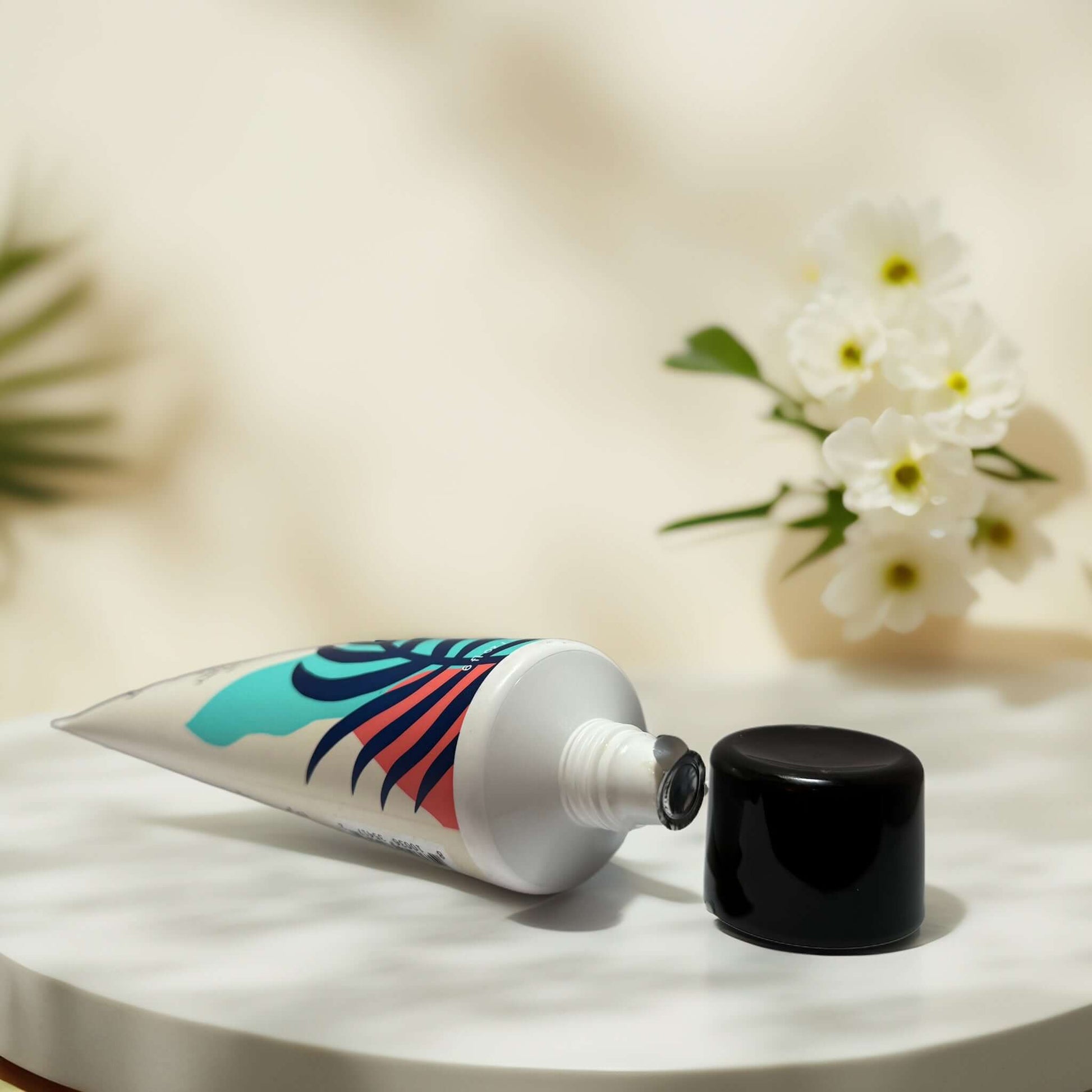 Cooling Scalp Mud Mask tube on marble surface with flowers
