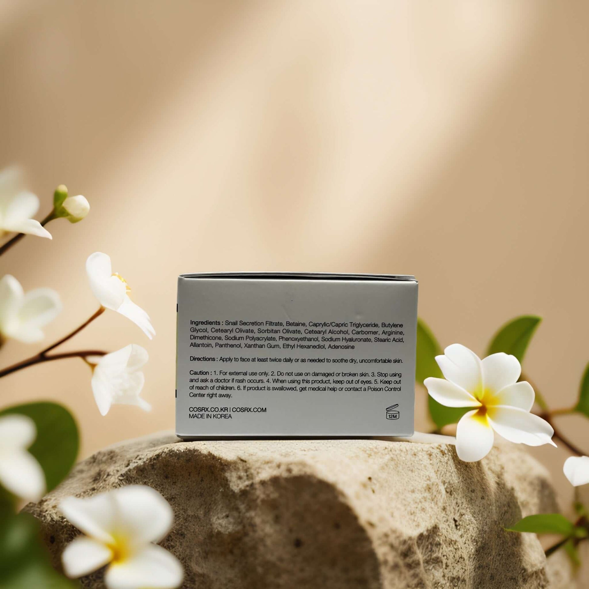 COSRX Hydrating Repair Advanced Snail 92 Facial Cream ingredients on packaging with floral background.