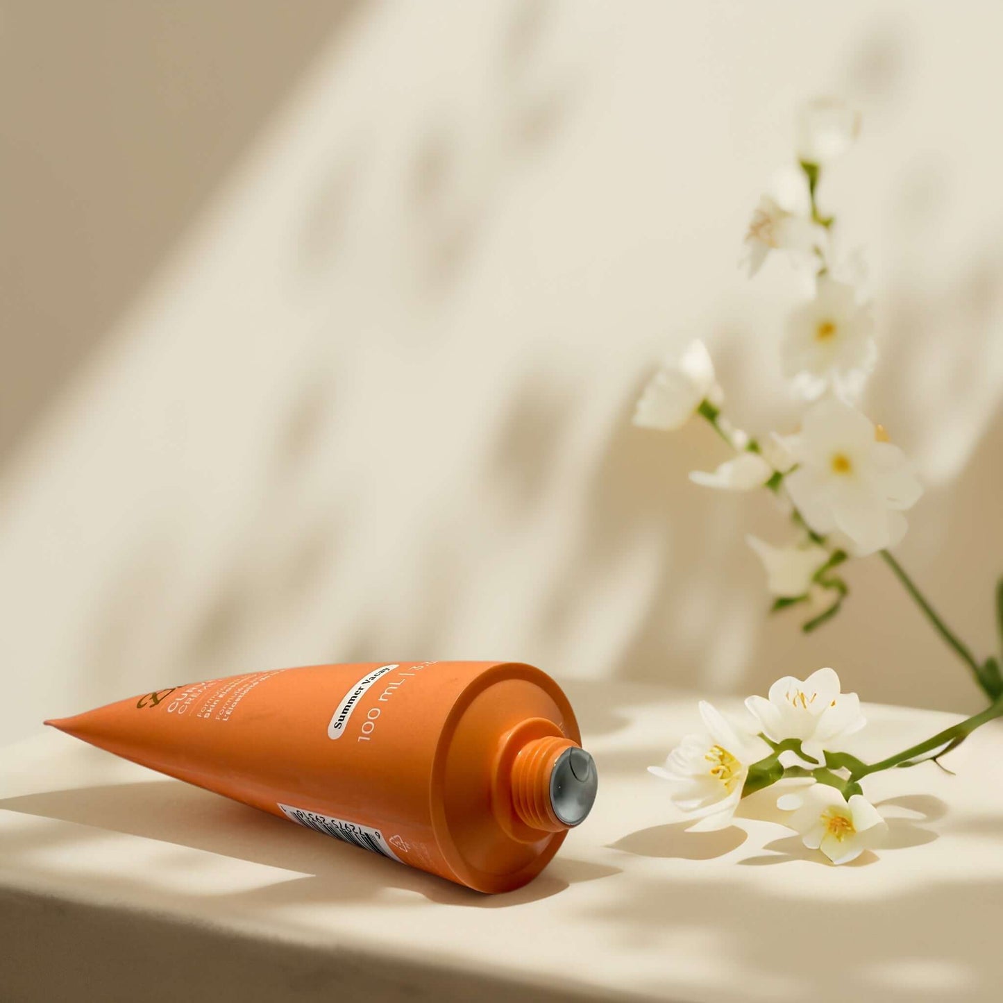 Bush Balm Curve Cream in orange tube with white flowers.