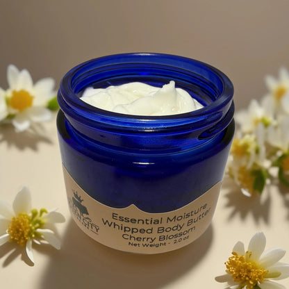 Cherry Blossom Whipped Body Butter from Queen City Skincare in blue jar surrounded by flowers.