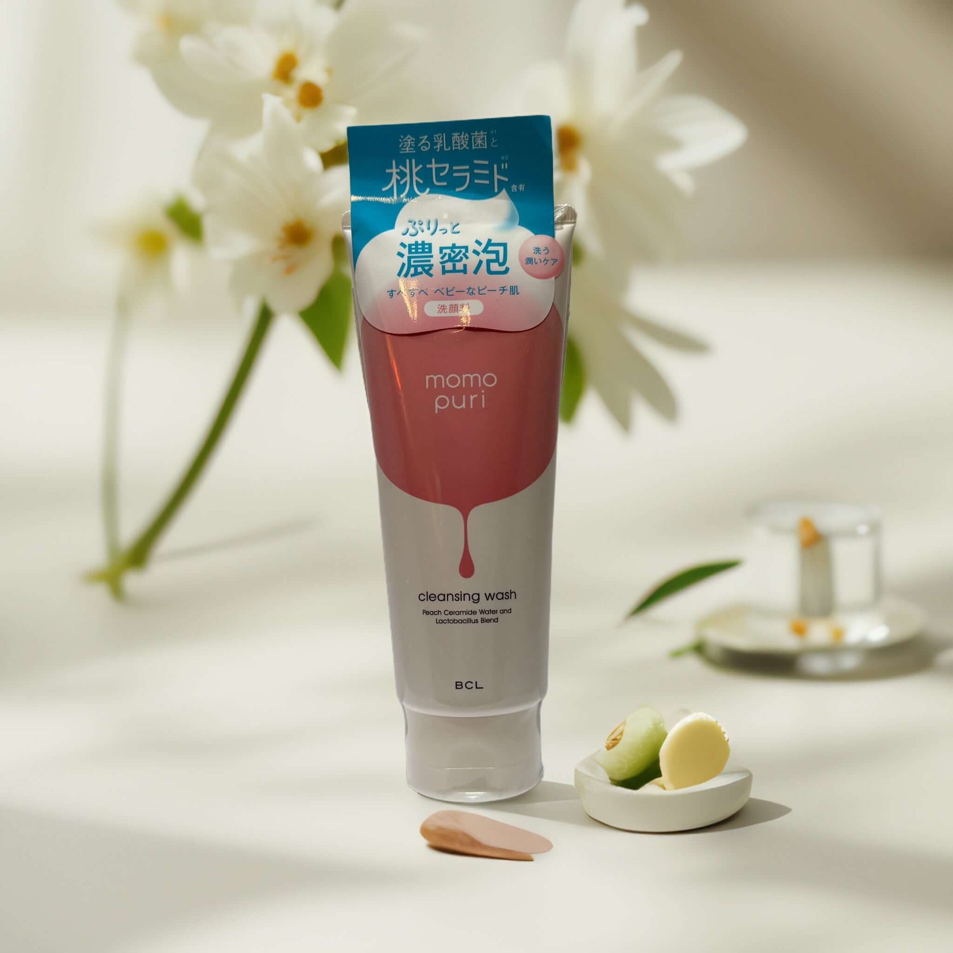 Momo Puri Peach Ceramide Cleansing Wash in a tube with floral backdrop.