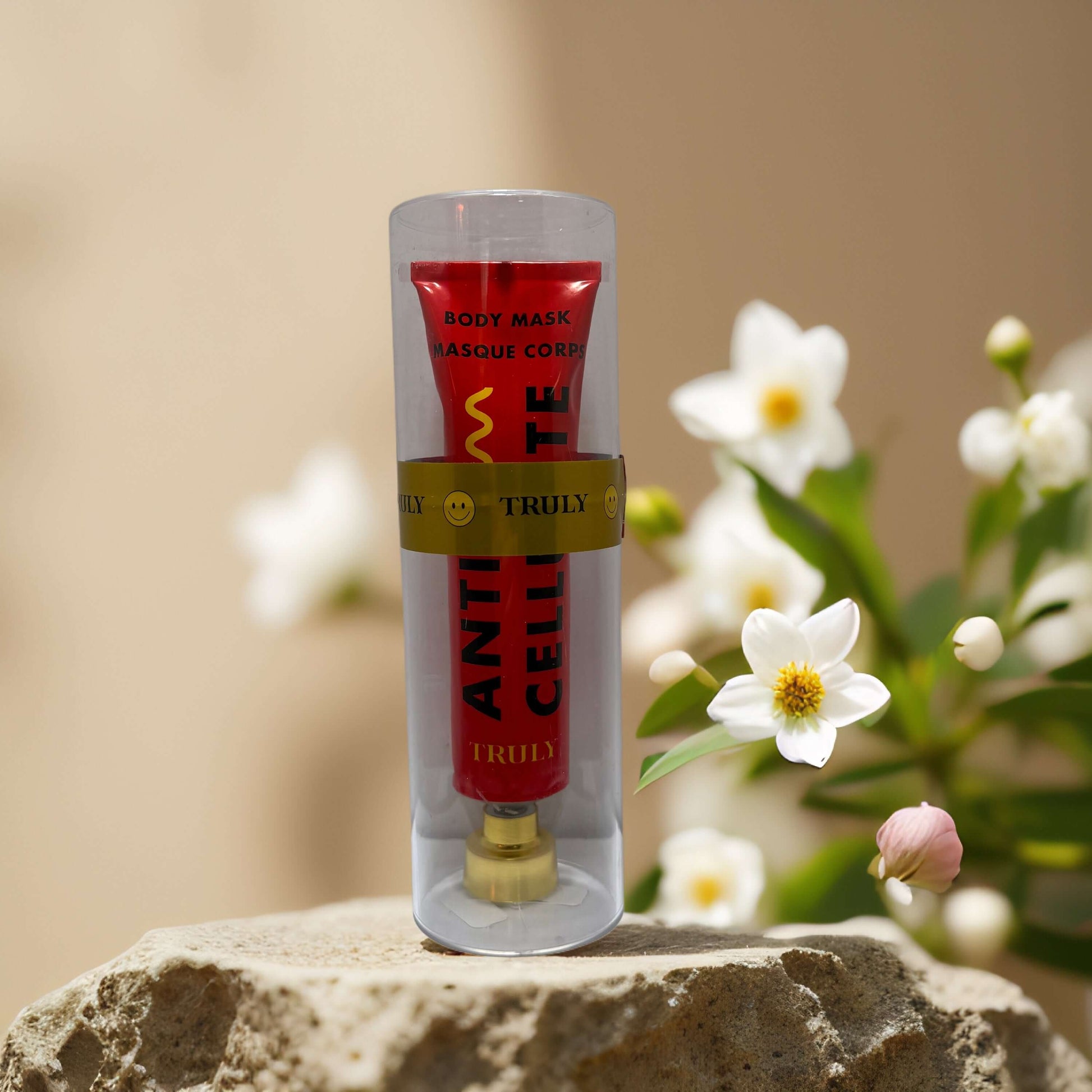 Truly Anti-Cellulite Body Mask in red tube, 3 fl oz, surrounded by white flowers on a stone surface.